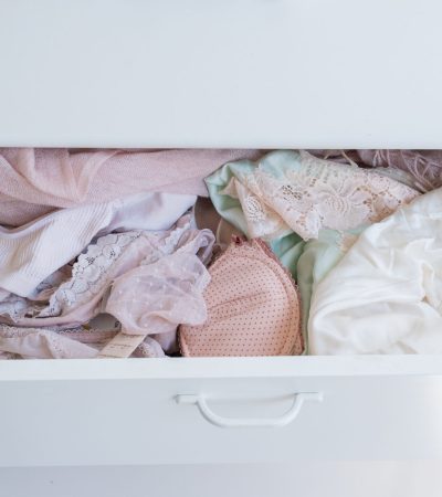 High angle close up of messy white drawer full of pink and cream women's underwear (selective focus)